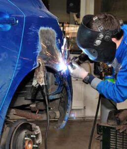 Expert auto body technician performing paintless dent removal and panel replacement