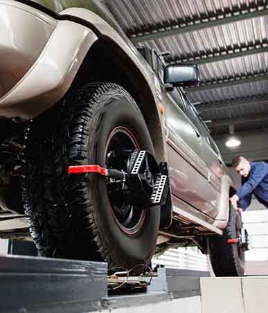 Mechanic adjusting the suspension and performing a precision wheel alignment on a vehicle